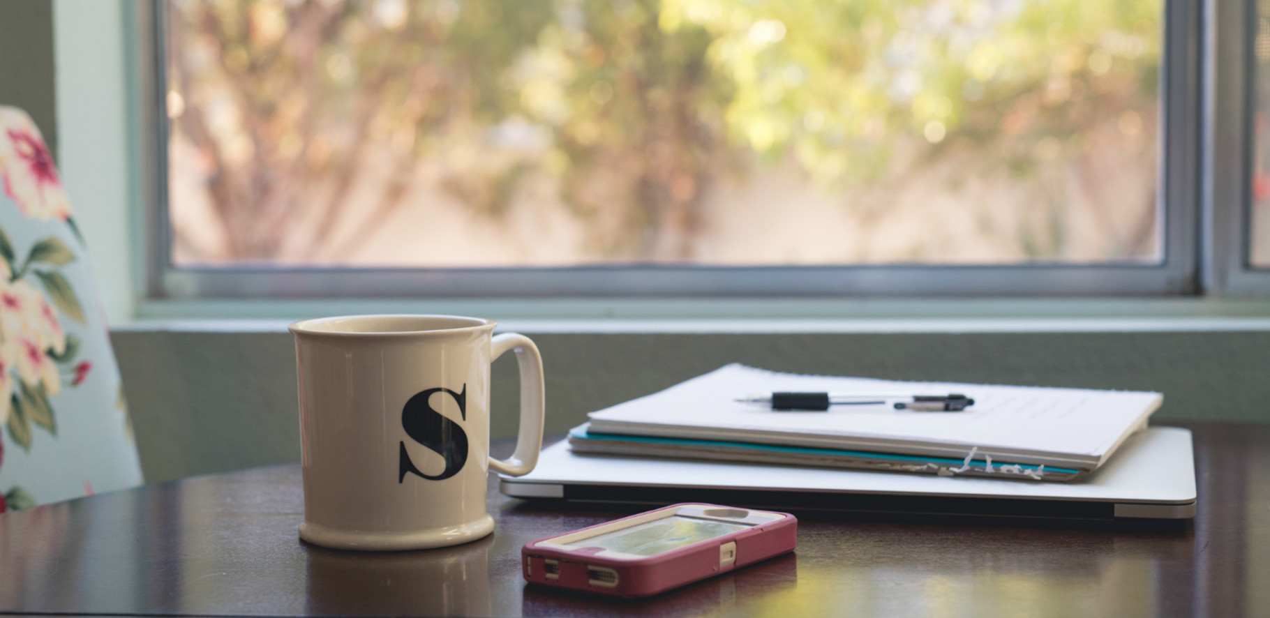 coffee cup and phone with project management papers on table