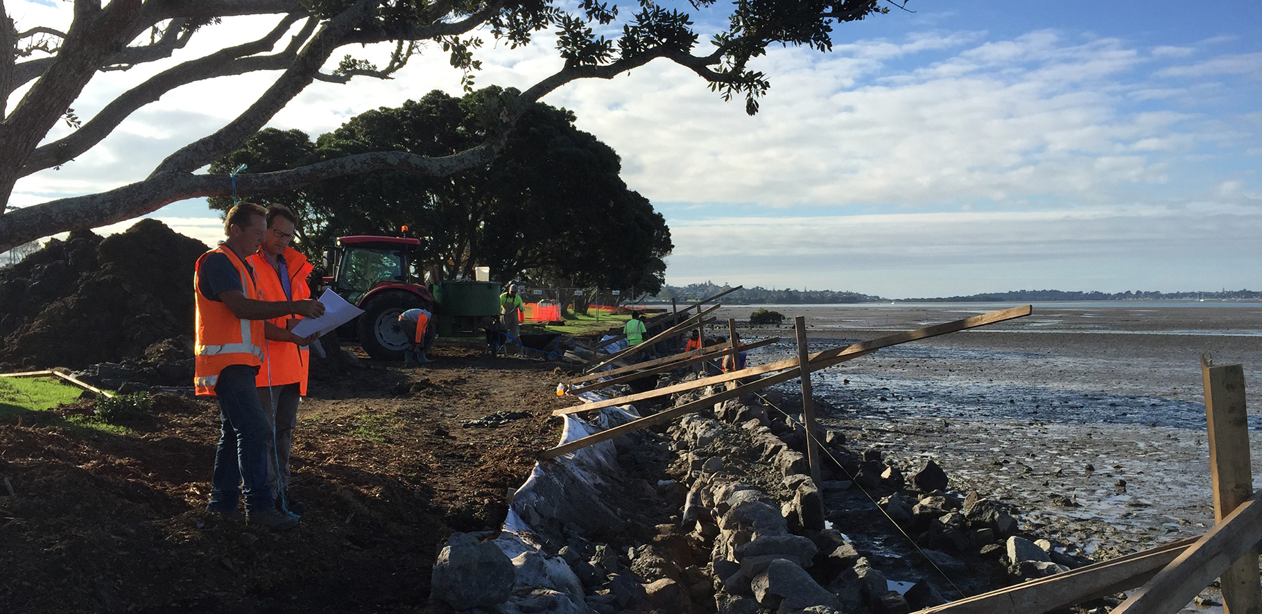 construction people in the progress of fixing a sea wall looking at plans